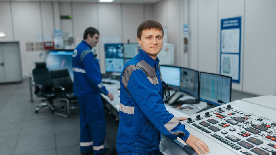 Two technicians at the consoles of an industrial control room