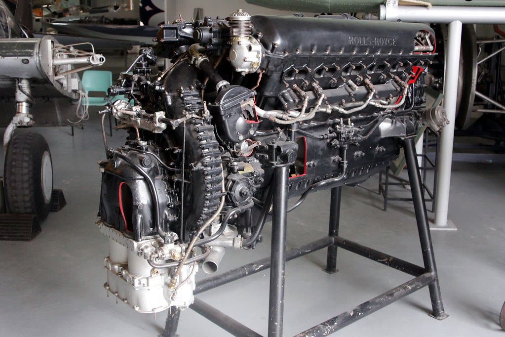 A Rolls-Royce Merlin engine on a display stand in a museum hangar