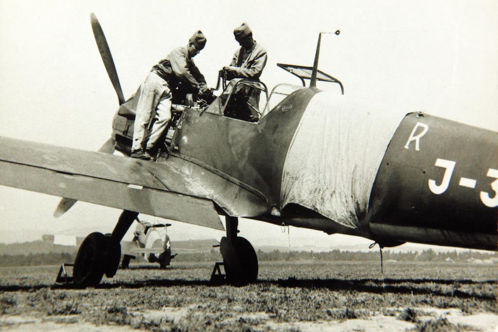 Two ground crew working at the cockpit of a Messerschmitt Bf 109 E on an airfield